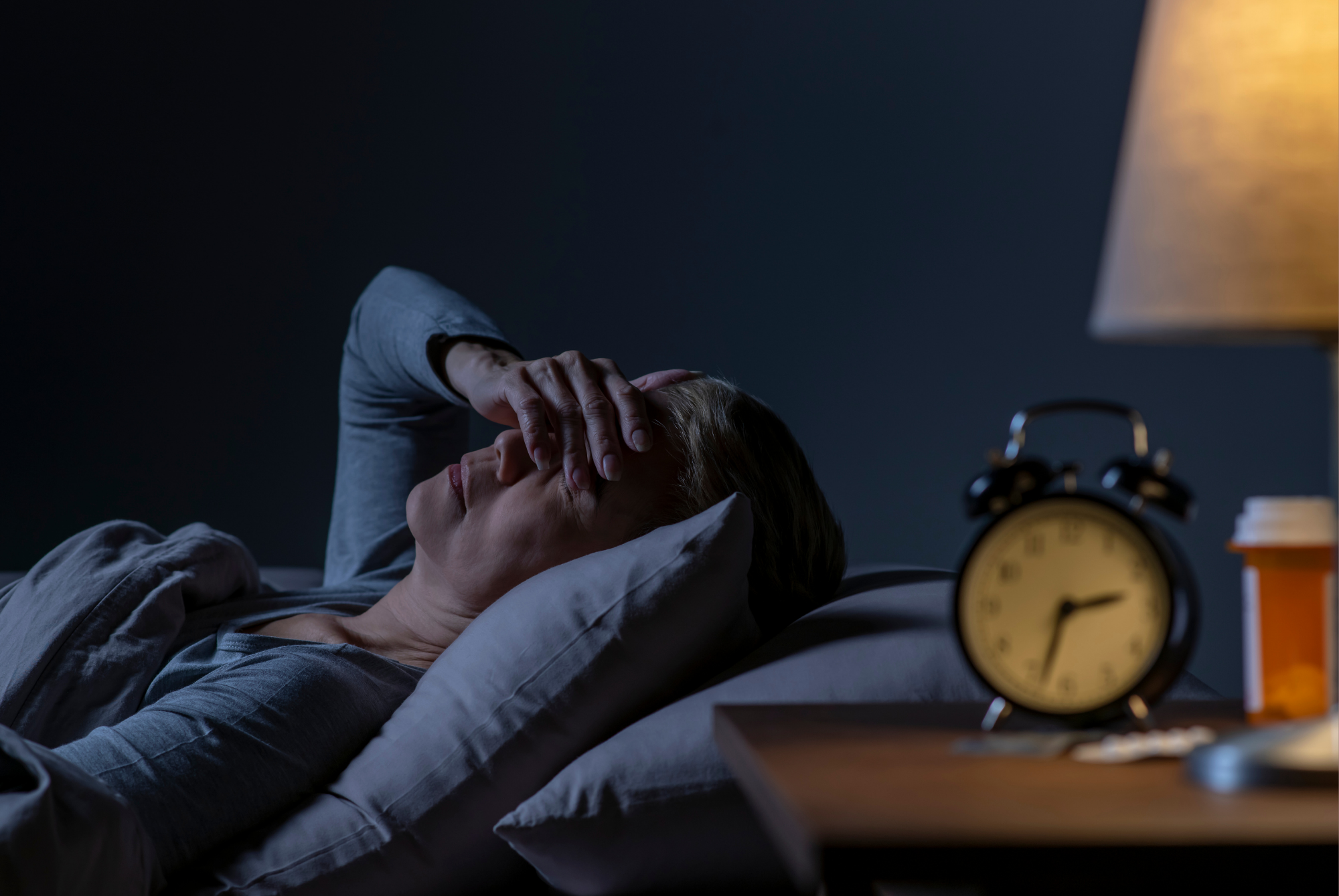 Person lying awake in bed unable to sleep because of allergy symptoms