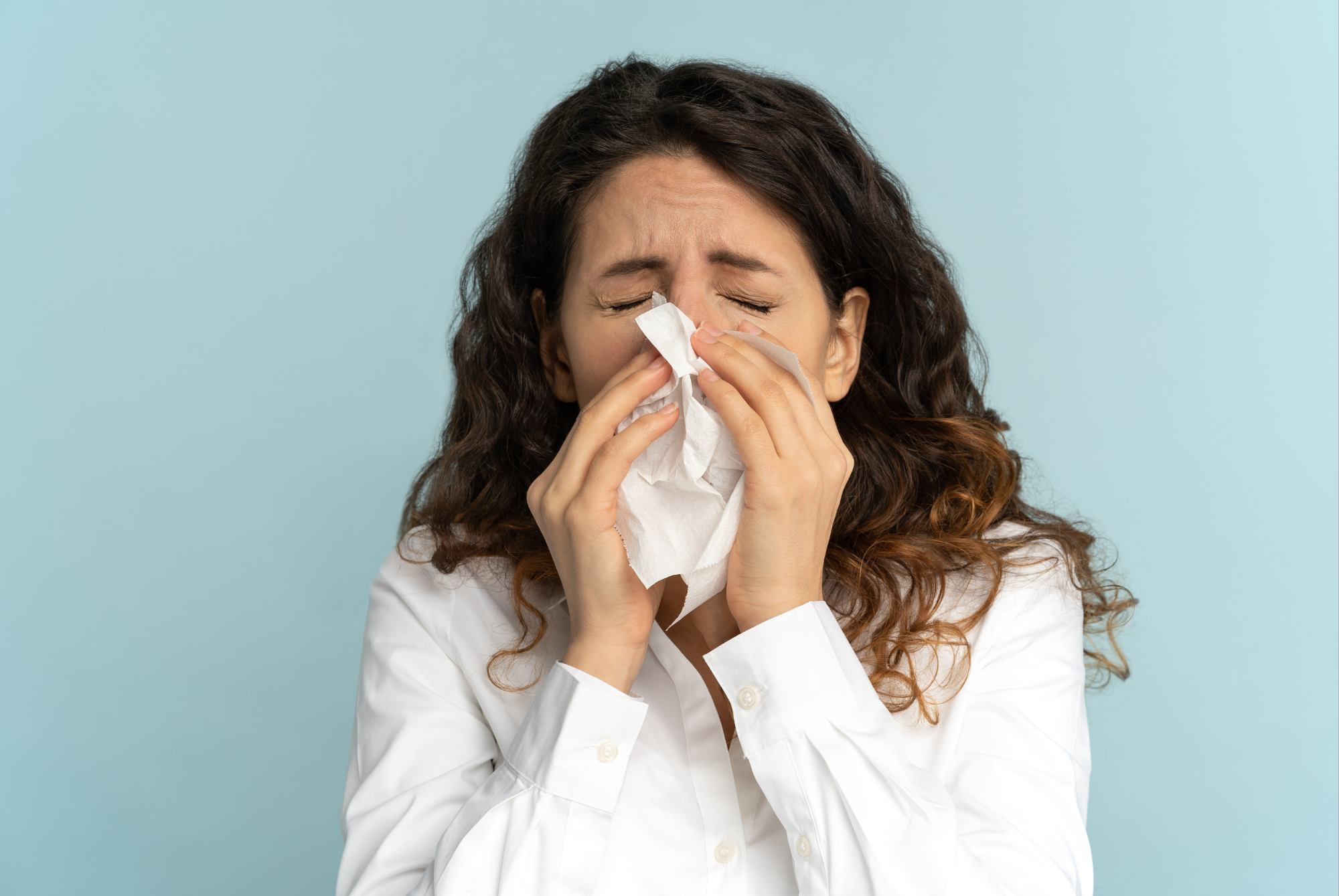 Woman sneezing into a tissue from prolonged allergen exposure